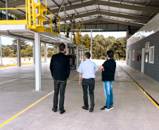 Na foto estão 3 homens de costas, sendo, da esquerda para a direita, o presidente do IPEM/PR, Dr. Cesar Mello, Shiniti Honda, diretor de metrologia e qualidade e Michel A. Ravazi, gerente da regional de Maringá.